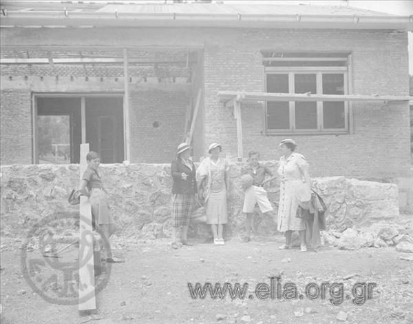 Iris Miliaraki, mrs Nikolaidis with her sons and a woman standing in front of a newly built building