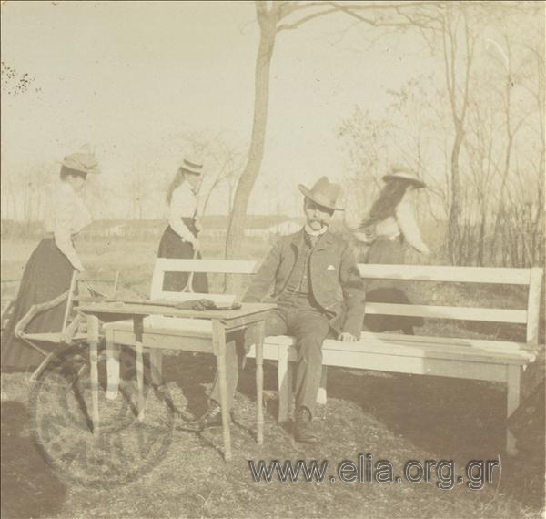 Άνδρας και τρεις νεαρές γυναίκες με ρακέτες του τέννις σε πάρκο.