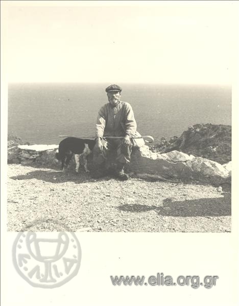 Shepherd Nikolas seated with a dog at his side