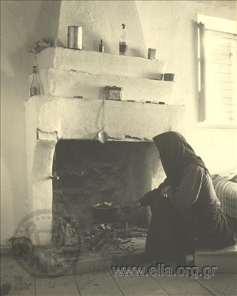 An old woman cooKing in the oven of a country house.