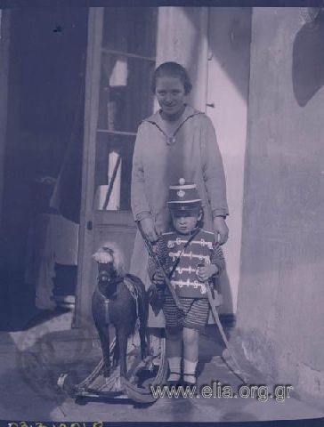 Portrait of a woman and a boy dressed as a soldier with toys.