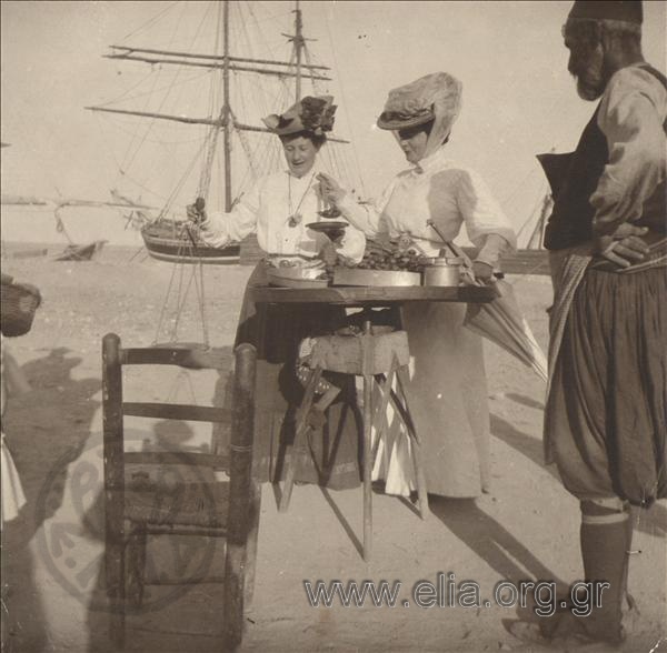 Two women at the stall of a pedlar on the beach , an excursion