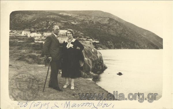 The Louϊzos Manouilidis and wife on the beach ; a settlement in the background.