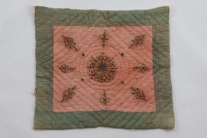 Baby quilt, pale pink cotton square with laid and couched gold embroidery, central floral ornament surrounded by sprays.