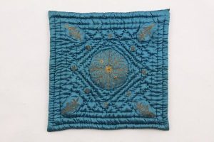 Baby quilt, cerulean blue silk satin with laid and couched gold embroidery, central floral ornament, diagonally placed corner motifs and rhombically arranged stars.