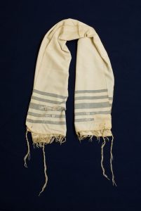 Prayer shawl, cream silk with grey-blue stripes along the edge, cream square corner reinforcements.