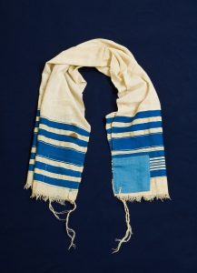 Prayer shawl, cream cotton with cobalt blue stripes along the edge, light blue square corner reinforcements.