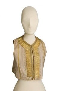 Cream waistcoat with woven gold stripes and floral pattern, round close-fitting neckline, edged with gold braid and embroidery.