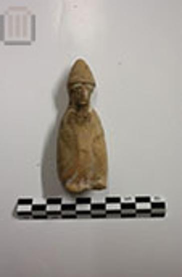 Figurine of seated male in wayfarer’s attire